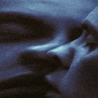 Das Bild zeigt ein blau-getöntes, abstraktes Gesicht in Nahaufnahme, mit weichen, verschwommenen Linien und Schatten.