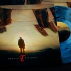 Vinyl-Cover mit "Mother of Millions", blauer Schallplatte; Silhouette einer Person vor flatternden Stoffen im Wind.