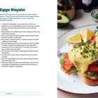 **Text:** "Eggs Royale" - Rezept mit pochierten Eiern, Avocado, geräuchertem Lachs und Trüffel-Hollandaise auf Brioche.  
**Beschreibung:** Zwei reichhaltig belegte Brotstücke mit Soße und Kräutern auf einem Teller.