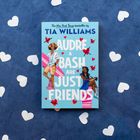 Buchcover: "Audre & Bash Are Just Friends" von Tia Williams. Hellblauer Hintergrund, zwei gezeichnete Personen, rote Herzen.