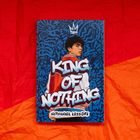 KING OF NOTHING in großer Schrift, darunter "Nathanael Lessore". Junge mit Krone, Illustration vor blauem Grafitti-Hintergrund.