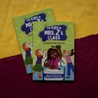 "The Kids in Mrs. Z’s Class: Fia Hosein Finds Her Beat" auf grünem Hintergrund. Illustration von Kindern mit Instrumenten.