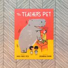 "The Teacher's Pet," illustriert von Zachariah Ohora. Ein großer grauer Dinosaurier neben einem Tisch mit einem Lehrer und Schülern.