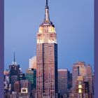 Im Vordergrund steht das Empire State Building bei Dämmerung, umgeben von weiteren hohen Gebäuden.