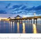 Fort Myers Pier at Sunset. Kalenderblatt mit Pier bei Sonnenuntergang, reflektierte Lichter im ruhigen Wasser, blauer Himmel.