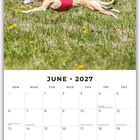 "JUNE 2027" steht oben. Darunter ein Hund in rotem Rennoverall, läuft über eine blühende Frühlingswiese.