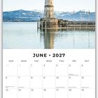 Text: "June 2027" mit Kalendertagen.  
Ein Leuchtturm steht am Wasser, im Hintergrund Berge.