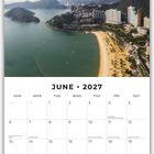 „JUNE 2027“ steht oben auf einem Kalenderblatt mit einer Luftaufnahme einer Bucht mit Strand und Gebäuden.