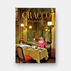 "CRACCO IN GALLERIA" in goldener Schrift. Ein Clown im roten Anzug sitzt in einem eleganten Restaurant.