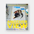 „ANOTHER VIEW“ in großen gelben Buchstaben. Ein Künstler arbeitet an einem ausgeschnittenen Kunstwerk auf dem Boden.