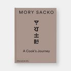 Text: "MORY SACKO, A Cook’s Journey, PHAIDON."  
Beschreibung: Schlichtes Buchcover in Beige.
