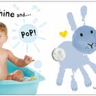 "Bubbles shine and... Pop! Bunnies nuzzle noses." Ein lachendes Baby in einer Badewanne und gezeichnete Hasen in sanften Farben.