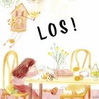 Text: "LOS!"
Illustration: Kind am Tisch, isst aus einer Schüssel. Deko und Spielzeug umgeben den Tisch.