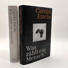 "Was zählt ein Mensch?" von Carolin Emcke. Zwei Bücher, eins offen, das andere zeigt das Cover mit schwarzen Sandalen.