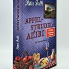 "Apfelstrudel-Alibi", Rita Falk, ein Provinzkrimi. Korb mit Äpfeln, Küken, Apfelstrudel auf kariertem Tuch, Foto mit Wohnmobil.