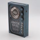 "AMOK SPIEL, SEBASTIAN FITZEK" auf einem alten Radio-Design. Das Buch sieht aus wie ein Retro-Radio mit Knöpfen.
