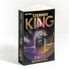 Buchcover: "Stephen King", "DREI", "Der Dunkle Turm", "Roman". Eine Tür und ein fliegender Vogel im Hintergrund.