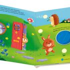Ein Hasenbau in einer grünen Wiese. Zwei Hasen und ein Igel sind fröhlich beim Spielen in der Sonne. Bunte Blumen überall.