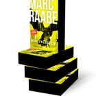 Buchcover mit großem, weißem Text: "MARC RAABE" und "IM MORGENGRAUEN". Gelber Hintergrund, jemand steht kopfüber.