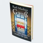 „Karl-Markus Gauß. Die Liebe kommt immer zu spät.“ Ein Zug mit blauen Türen und gelbem Licht.