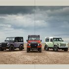 Inhalt: Kapitel über Land Rover-Geschichte und Innovation. Drei Geländewagen auf sandigem Untergrund unter bewölktem Himmel.