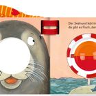 Text: Der Seehund lebt im großen Meer, da gibt es Fisch, den mag er sehr. Illustration eines Seehundes mit Loch für die Nase, Angel und Fische.