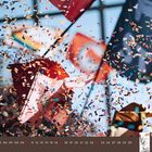 Kalender: Januar 2027. Farbenfrohes Konfetti schwebt vor wehenden Fahnen in der Luft.