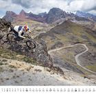 Kalendertage unten. Fahrradfahrer in Bergen, kurvige Straße im Hintergrund, bewölkter Himmel.