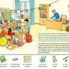 In einem Klassenzimmer sitzen Kinder an Tischen. Ein Lehrer sitzt am Schreibtisch. Spielzeug und Bücher sind im Raum verteilt.