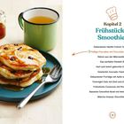 "Kapitel 2: Frühstück & Smoothies. Fluffige Pancakes mit Chocolate Chips. Links Pfannkuchen mit Sirup und ein Becher Tee."
