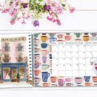 Kalenderseite Februar mit Tassenmotiven. Links Illustration eines rosa Hauses. Oben Blumen, rechts Tee.