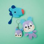 Drei gehäkelte Tierfiguren auf hellgrünem Hintergrund; ein blauer Fisch, ein lilafarbener Bär und ein kleiner lilafarbener Schlüsselanhänger.