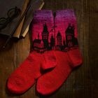 Rote Socken mit schwarzer Skyline, liegend auf Holztisch. Nebendran Bücher und eine Brille.