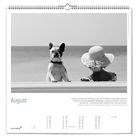 August. Zitat über die Magie des Vorlesens von Meghan Cox Gurdon. Ein Hund und ein Kind blicken zum Meer, in Schwarz-Weiß.