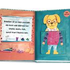 Text: "Draußen ist es nass und kalt, da muss was Warmes her: Stiefel, Weste, Pulli, sonst friert Pauline sehr. Zieh mich an!" Illustration von einem Hund in Winterkleidung.