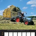 Juli 2027 Kalender: Ein Traktor zieht einen beladenen Heuwagen über ein Feld bei blauem Himmel.
