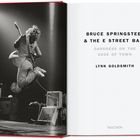 Text: "BRUCE SPRINGSTEEN & THE E STREET BAND DARKNESS ON THE EDGE OF TOWN LYNN GOLDSMITH". Links springt ein Musiker mit Gitarre.