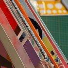 Es sind keine erkennbaren Texte vorhanden. Stapel bunter Papierblätter mit Mustern und Farben in einer gefächerten Anordnung.