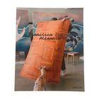 Text: "Francisco Sierra Alfombra". Eine Person hält einen parkettähnlichen Teppich, ein Hund beobachtet. Kunst im Hintergrund.