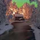 Kalenderseite mit einem Januar-Kalender. Verschneite Hütte am Fluss unter grünem Polarlicht und sternenklarem Himmel.