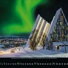 Kalendarium im unteren Bereich. Nordlichter über einer schneebedeckten, beleuchteten Kirche mit modernem Design in einer Winterlandschaft.