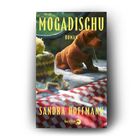 "MOGADISCHU" und "ROMAN" in gelber Schrift. Ein Plüschhund sitzt auf kariertem Stoff mit einem gehäkelten Becher daneben.