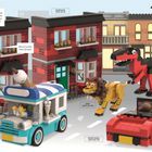 „Oma, schau mal! Ein Löwe und ein Allosaurus rennen hinter dem Eiswagen her!“ LEGO-Szene mit bunten Gebäuden.