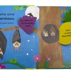 Ein Kinderbuch zeigt Fledermäuse am Baum, mit Texten über Schlaf und Insektenflug. Bunte Blätter und Blumen umgeben sie.
