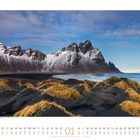 Kalendertage: 01 bis 31, Januar. Schneebedeckte Berge, schwarze Sanddünen mit Gras, blaues Meer und Himmel.