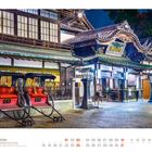 01 JANUAR: Historisches japanisches Gebäude mit traditionellem Dach und zwei roten Rikscha-Wagen davor, beleuchtet bei Nacht.