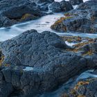 Links ist eine Kalender-Spalte für Januar. Rechts Blick auf Felsen im Meer bei Sonnenuntergang.