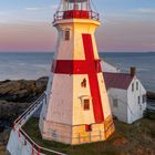 Kalenderblatt Januar, Leuchtturm mit rot-weißen Streifen am Meer, umgeben von Felsen und einem kleinen weißen Gebäude.