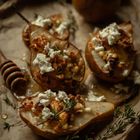 Drei Birnenhälften mit zerbröckeltem Feta, Nüssen und Kräutern belegt, auf rustikalem Papier arrangiert.