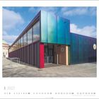 1 2027. Bahnhofsmission | Hamburg, Deutschland | Architektin: Cazzie B. Roth. Metallverkleidetes Gebäude mit blauen und roten Akzenten.